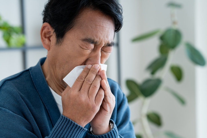 Middle-aged man blowing his nose in the living room